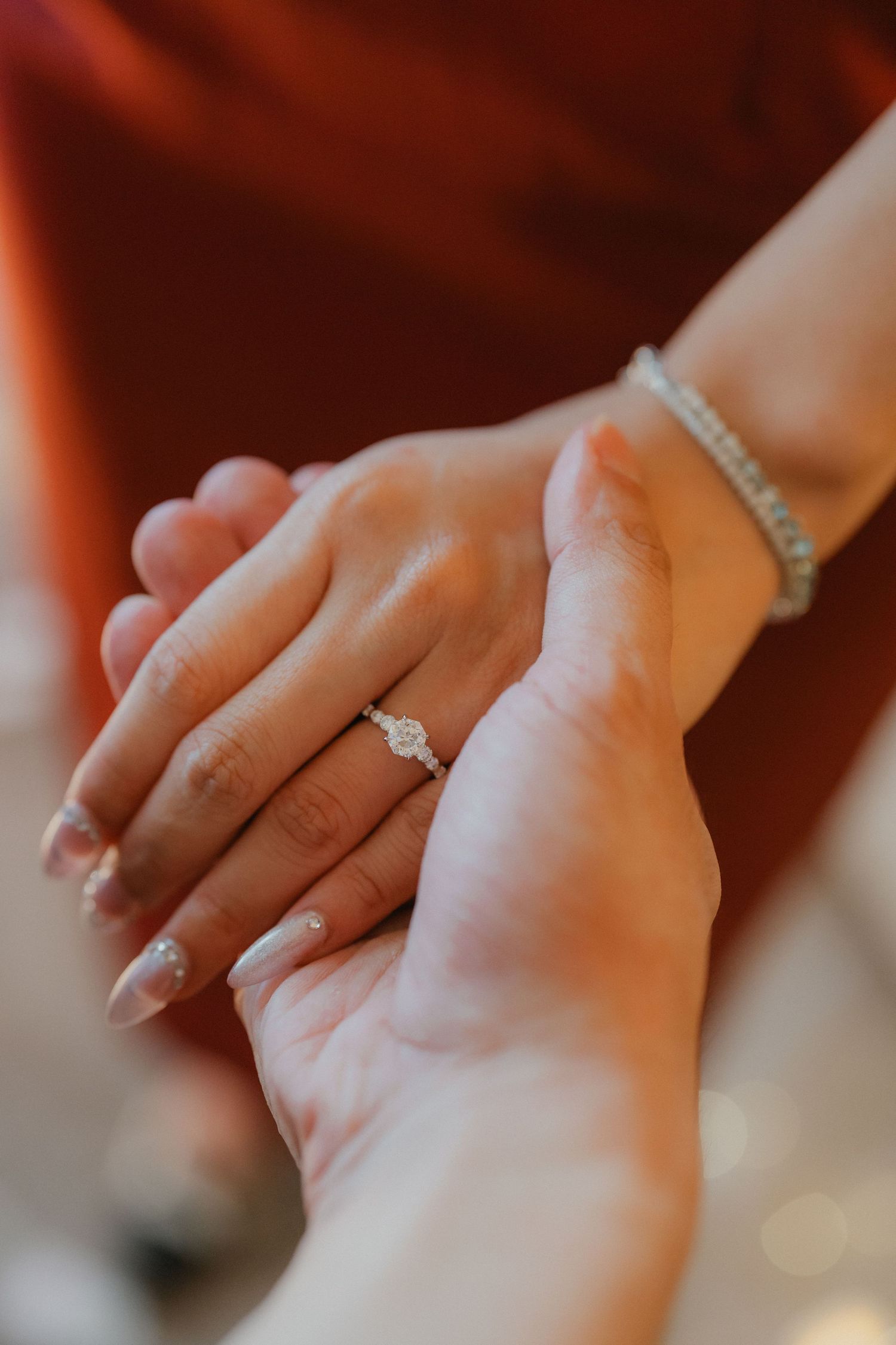 Close-up of hands showing engagement ring with diamond solitaire.