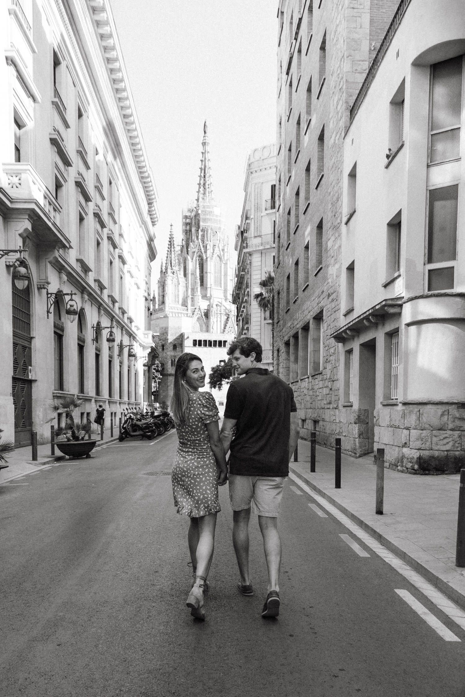Black and white photo of couple walking down historic European street.