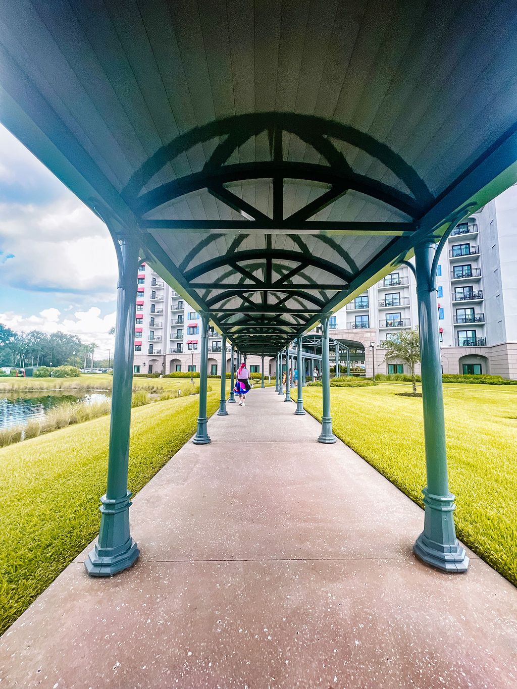 Covered walkway with blue and green architectural details leading through resort grounds.