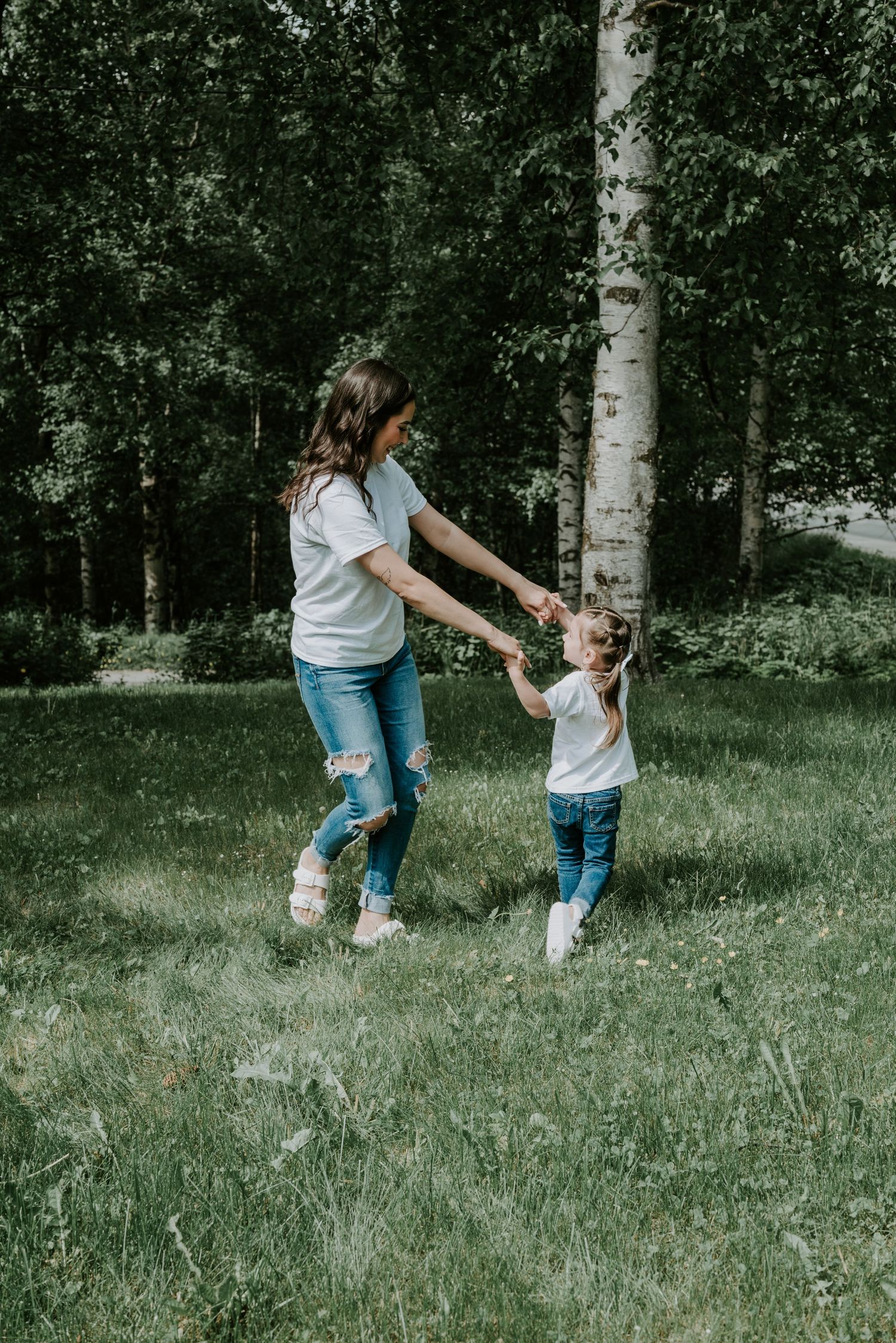 A sweet moment of dancing and playing in a lush forest setting with matching casual outfits and jeans.