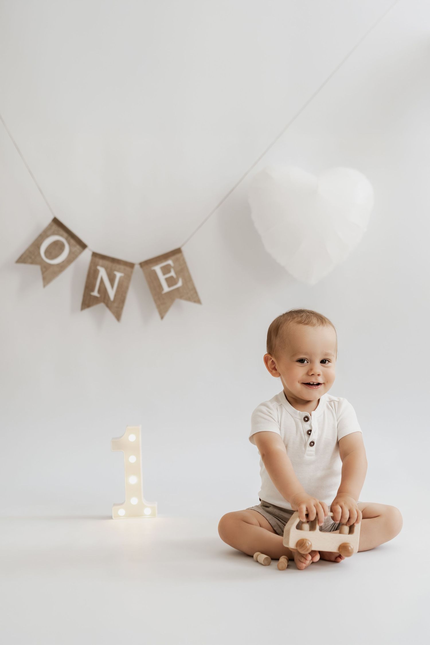 Kleiner Junge beim Geburtstagsfotoshooting im Fotostudio Stockerau, natürliches Geburtstagsfoto mit Luftballonzahl 1