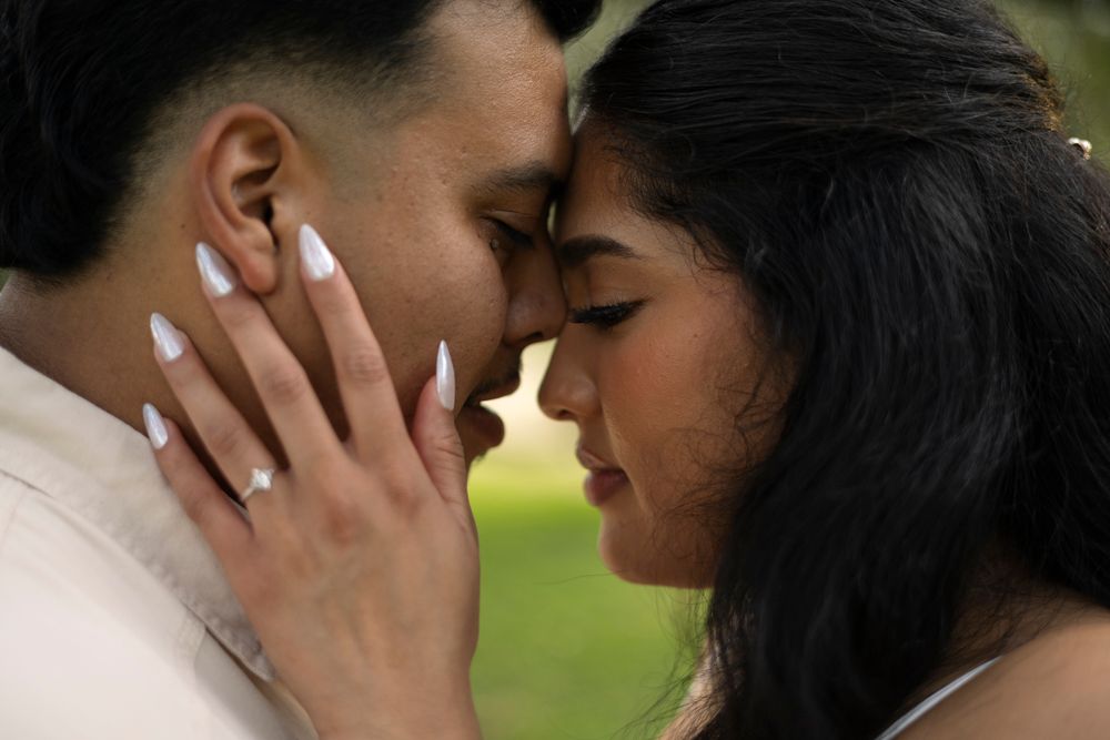 A romantic close-up photo of a tender kiss between a couple outdoors in a park setting.