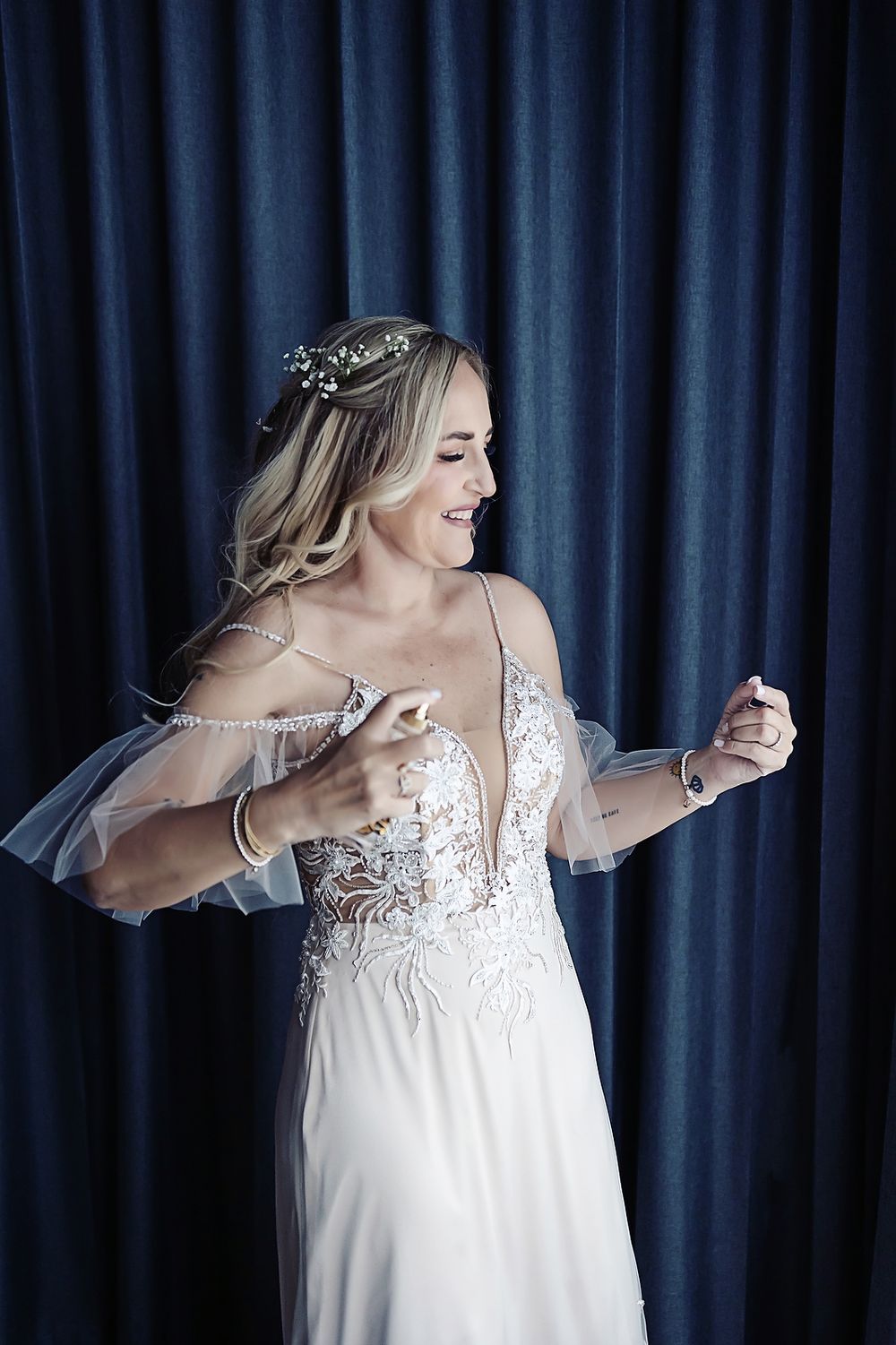 A flowing white wedding dress with lace detail is captured in motion against a dark blue backdrop.