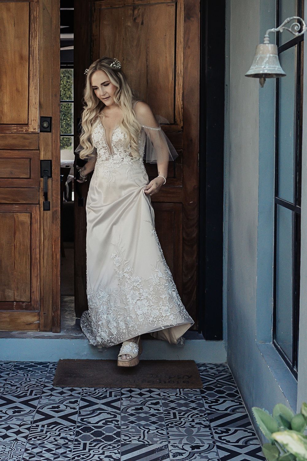 Four sequential shots showing a white wedding dress with lace details twirling on a patterned tile floor near wooden doors.