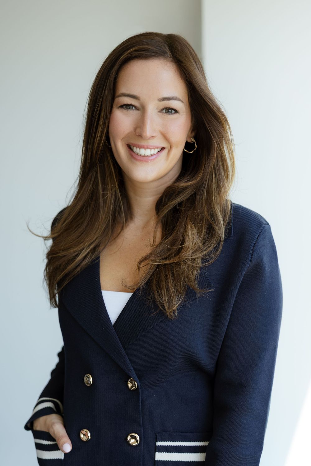 Portrait photo series showing different angles of someone wearing a navy blazer with gold buttons against a bright background.
