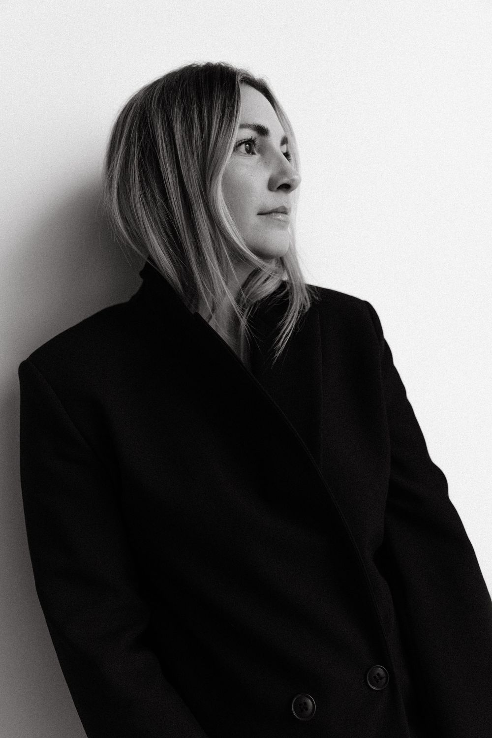 A series of profile portraits in black and white showing a person in a dark coat gazing upward against a light background.