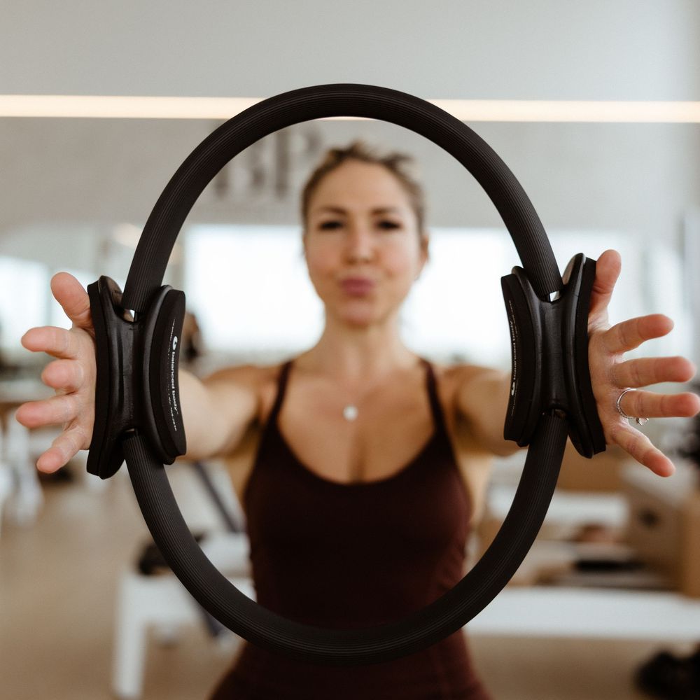 Athletic person holding a Pilates ring exercise equipment during a workout session in a bright fitness studio.