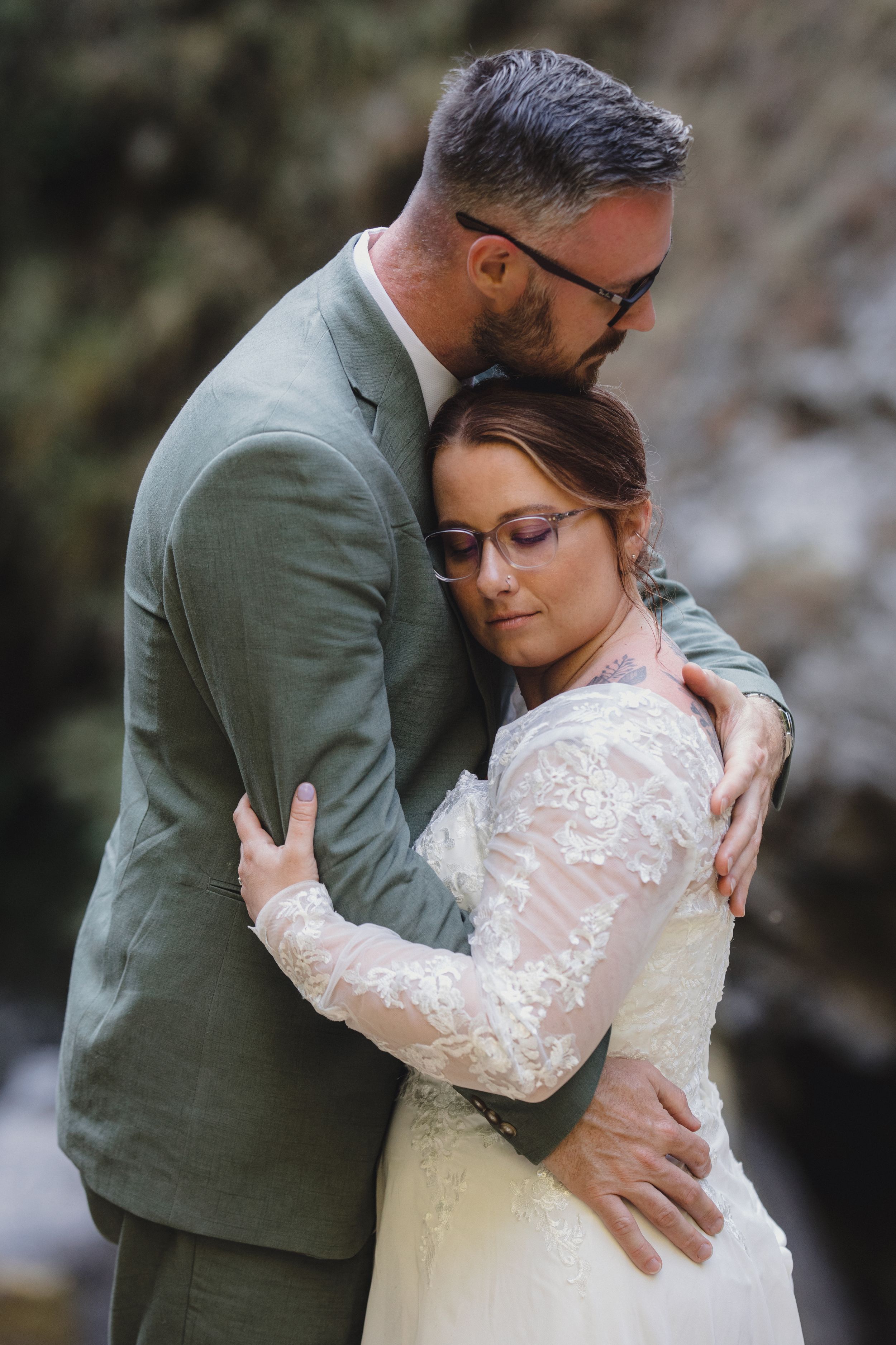 A tender embrace captured between a couple in wedding attire against a natural backdrop.