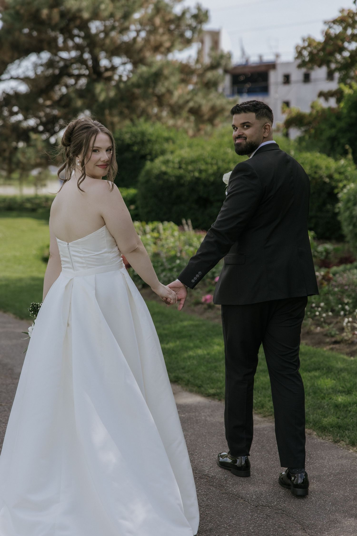 A loving embrace in a sunlit meadow at dusk, with flowing white dress and burgundy attire creating a romantic scene.