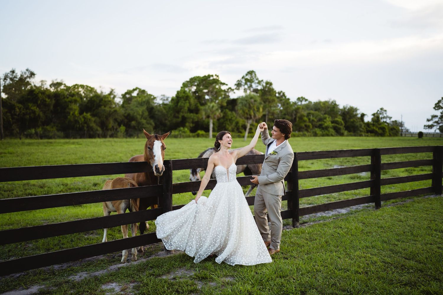A couple shares an intimate moment on a horse farm as they celebrate their wedding day next to a wooden fence.