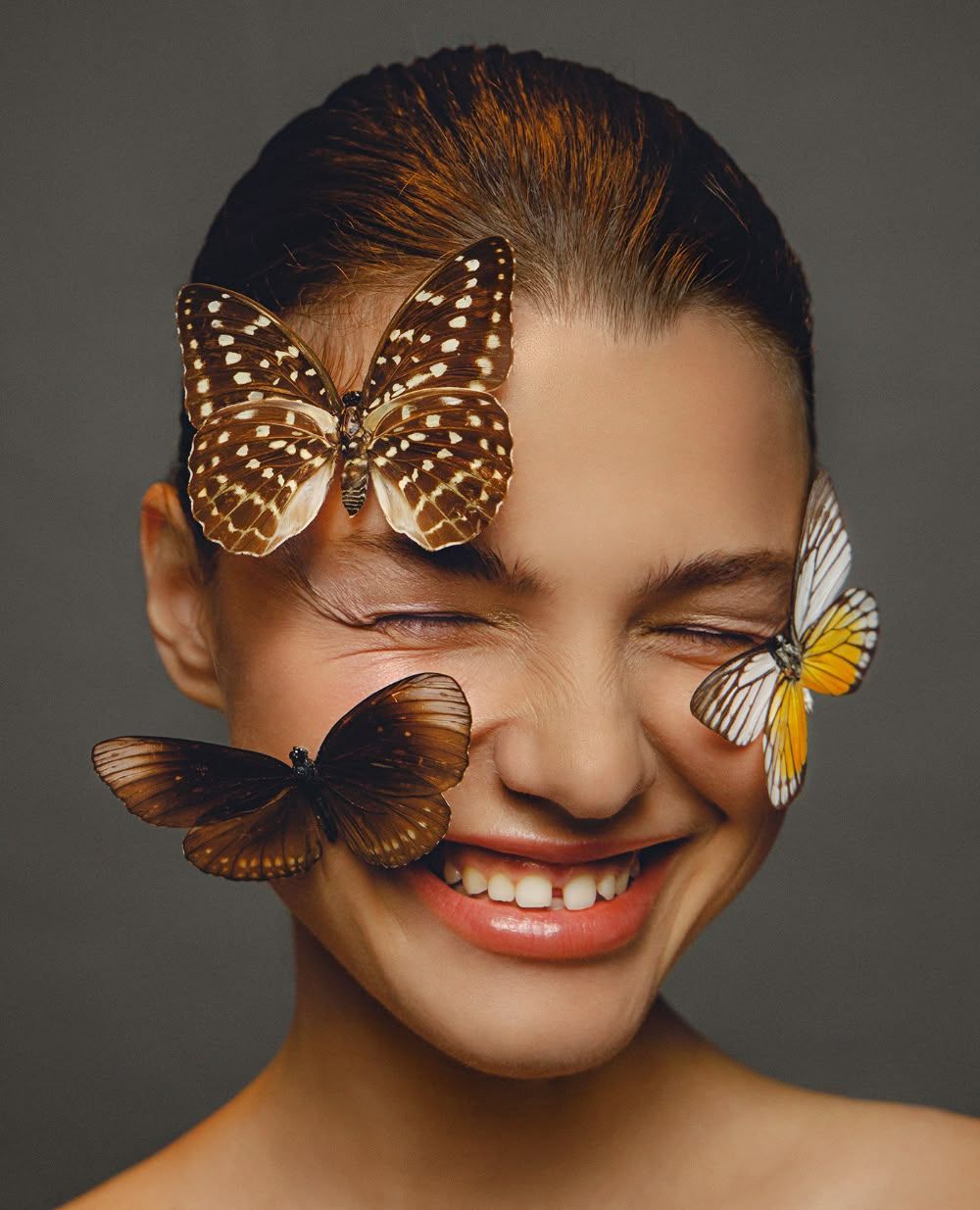 Beautiful portrait with three butterflies adorning the subject against a dark background.