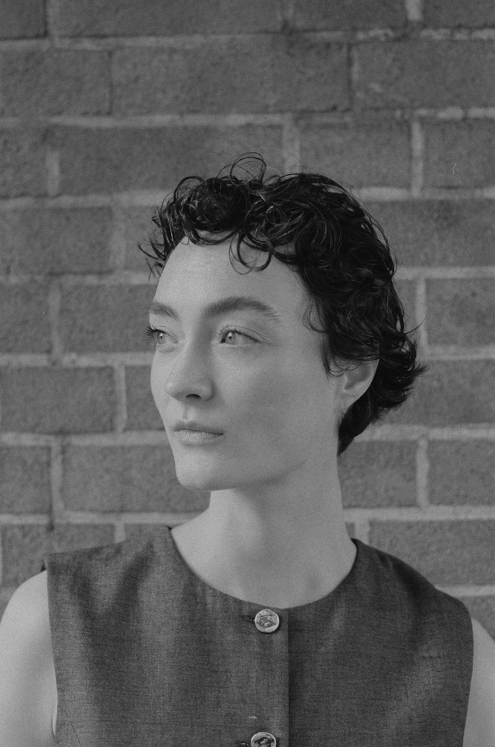Black and white artistic portrait series showcasing emotive poses against a brick wall background.