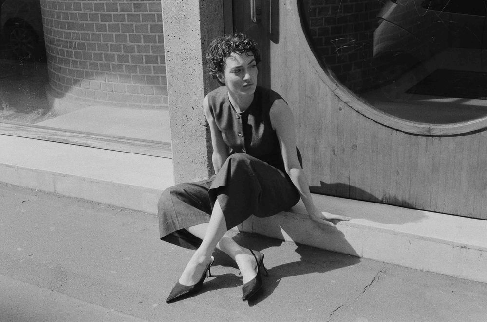 A series of black and white photographs showing someone perched on a ledge or windowsill with their legs visible.