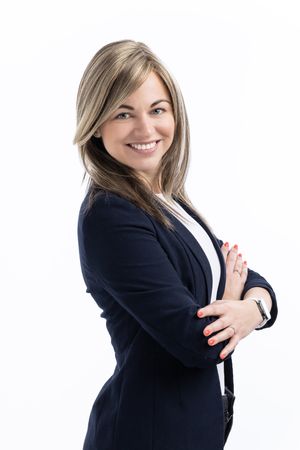 Professional woman in a black blazer posing confidently against a white background.