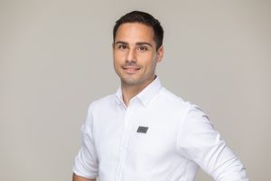 Professional headshot of someone wearing a crisp white dress shirt against a neutral gray background.