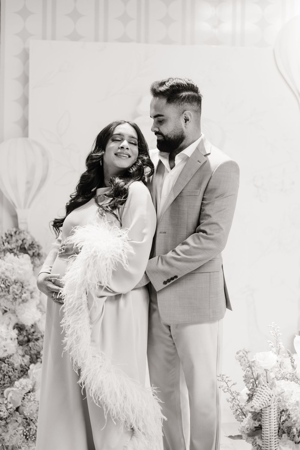 Black and white portrait of a pregnant woman and her partner embracing at a baby shower.