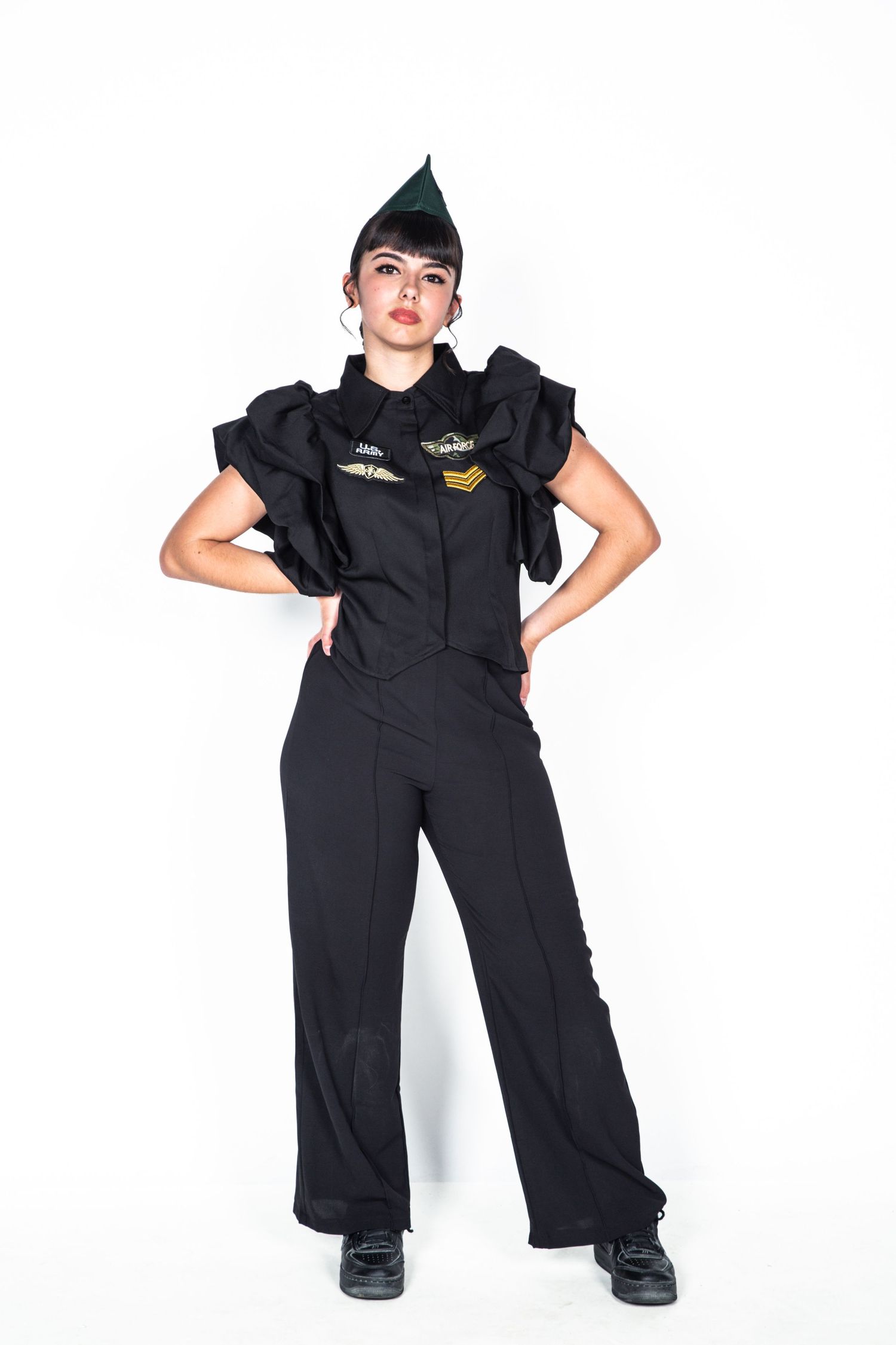 Person in black coveralls with patches posing in three different stances against white background.