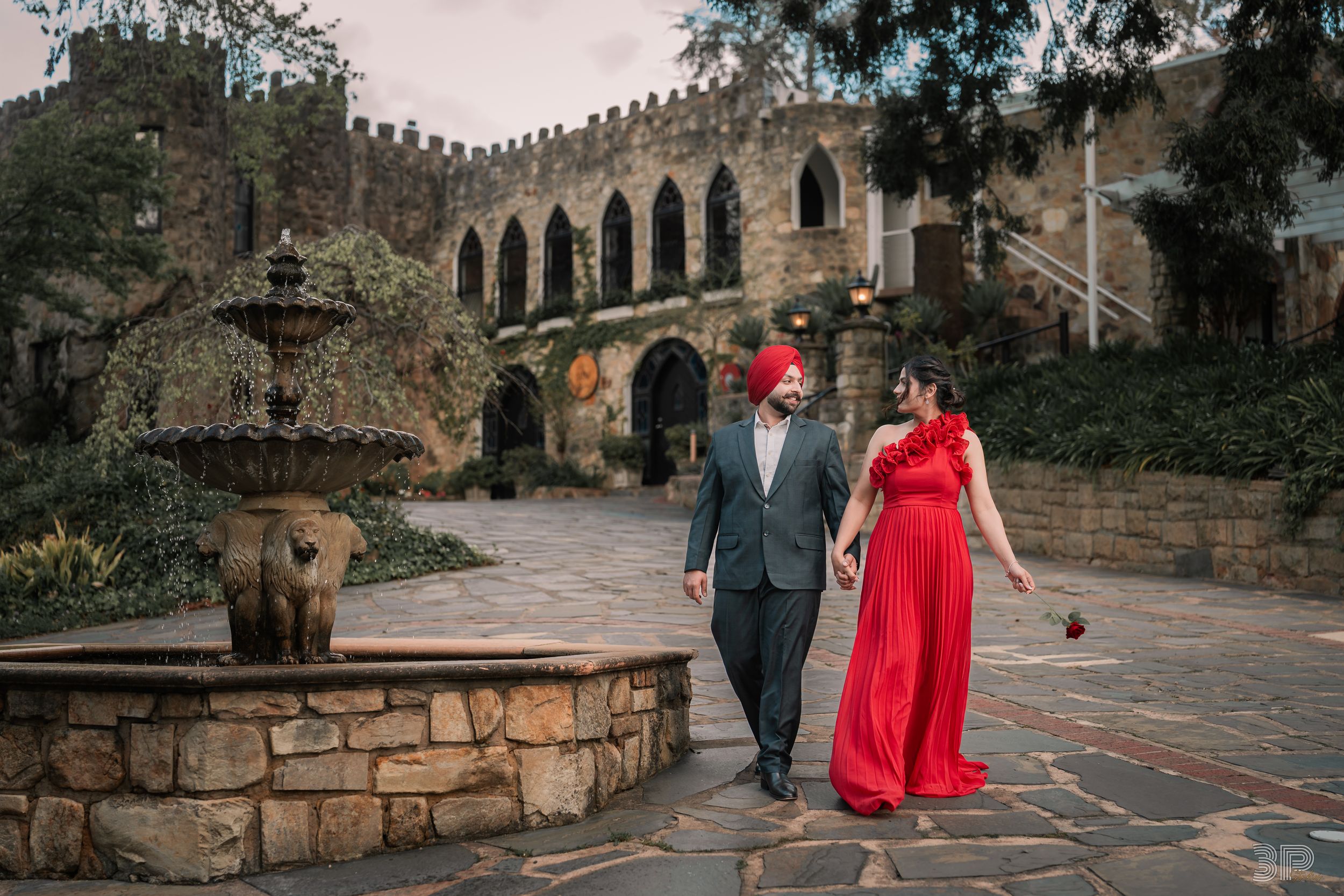 Romantic couple walking through historic stone architecture and pathways with woman in flowing red dress.