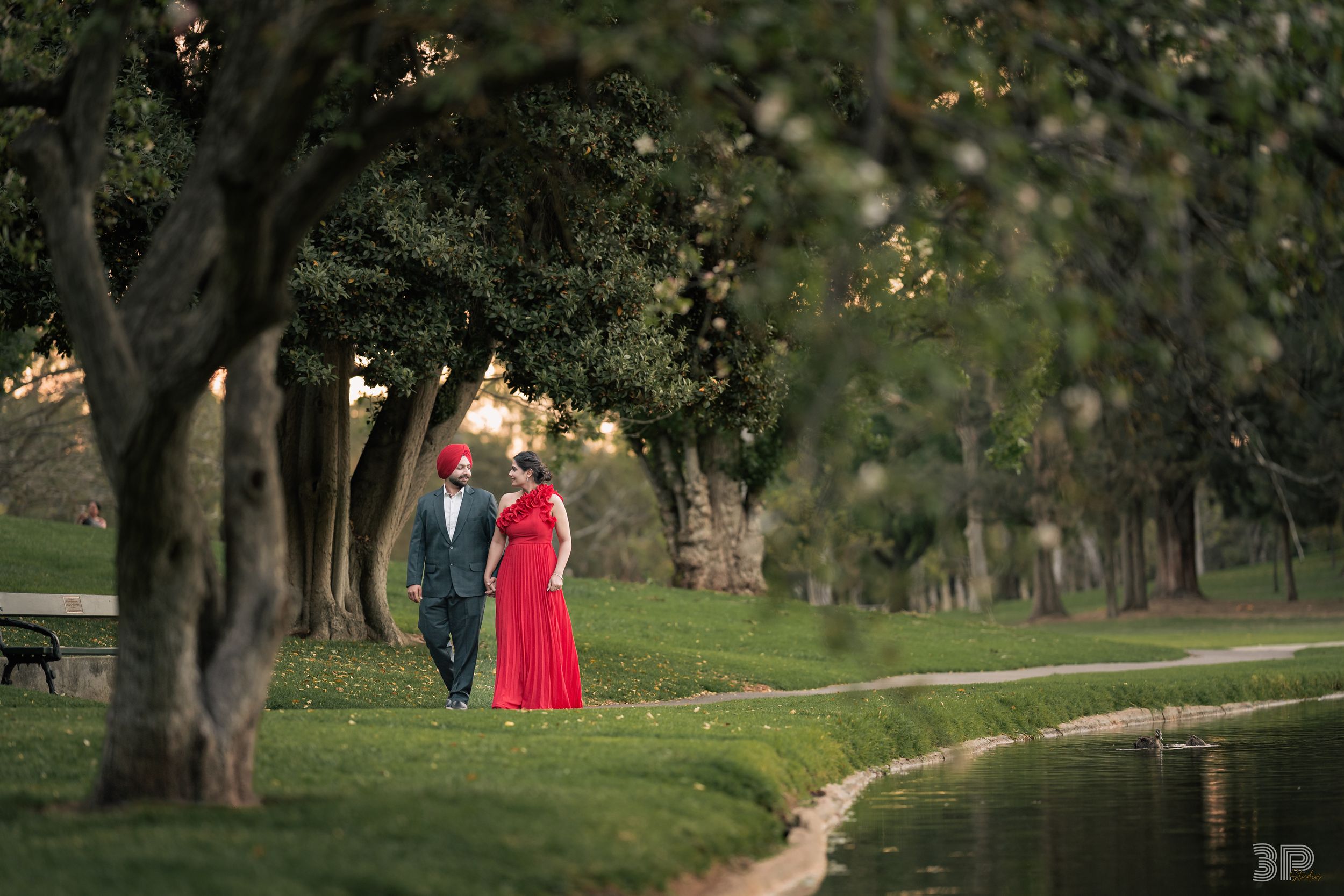 A tree-lined pathway in a park with a figure in red visible in the distance.