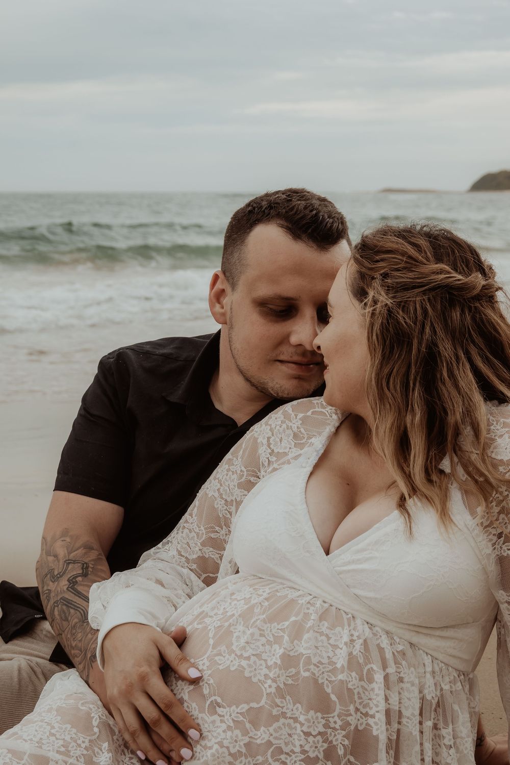 Intimate beachside moment captured in soft, muted tones during a central coast maternity photoshoot.