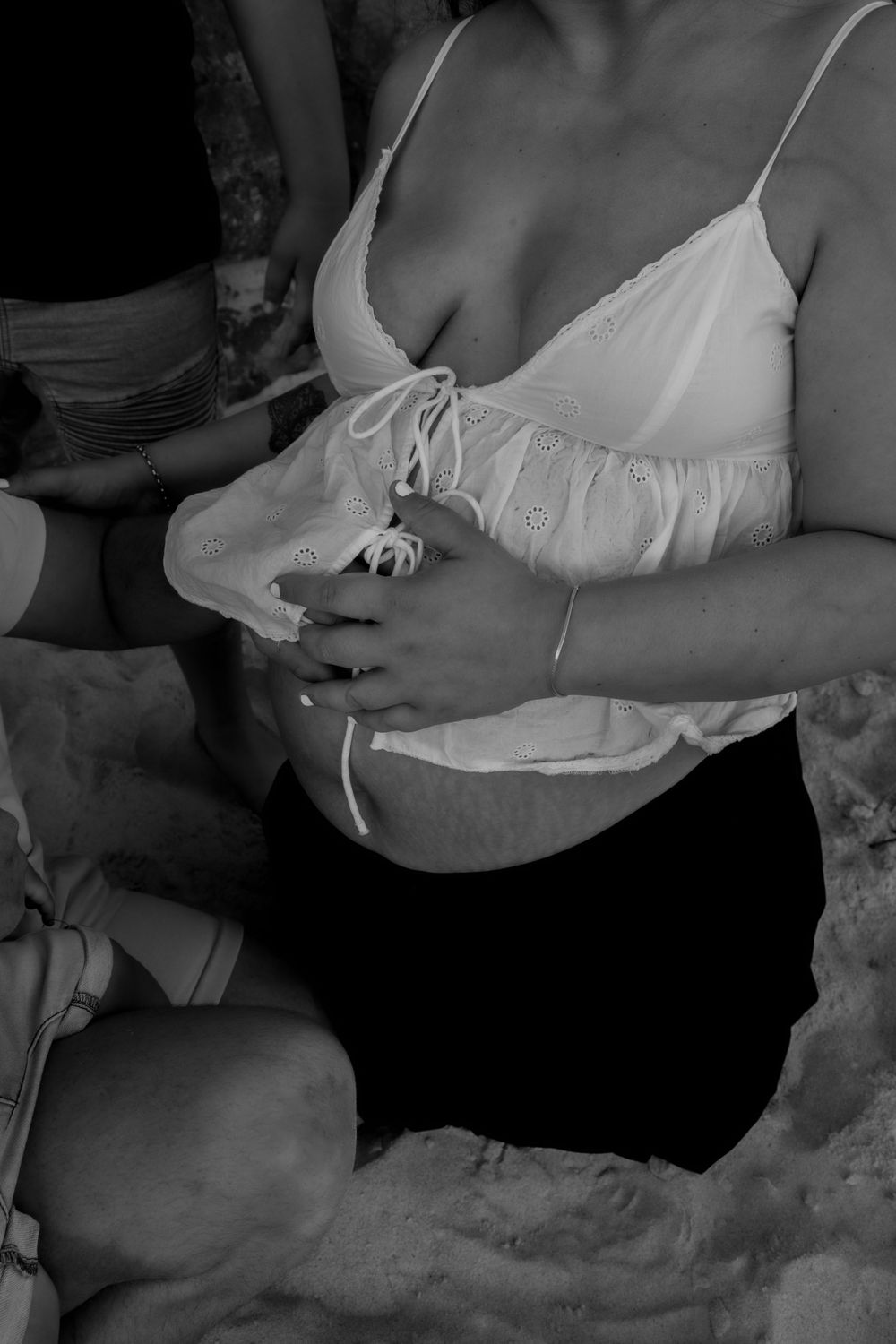 Close-up of hands gently cradling pregnant belly in black and white during a central coast maternity photoshoot.