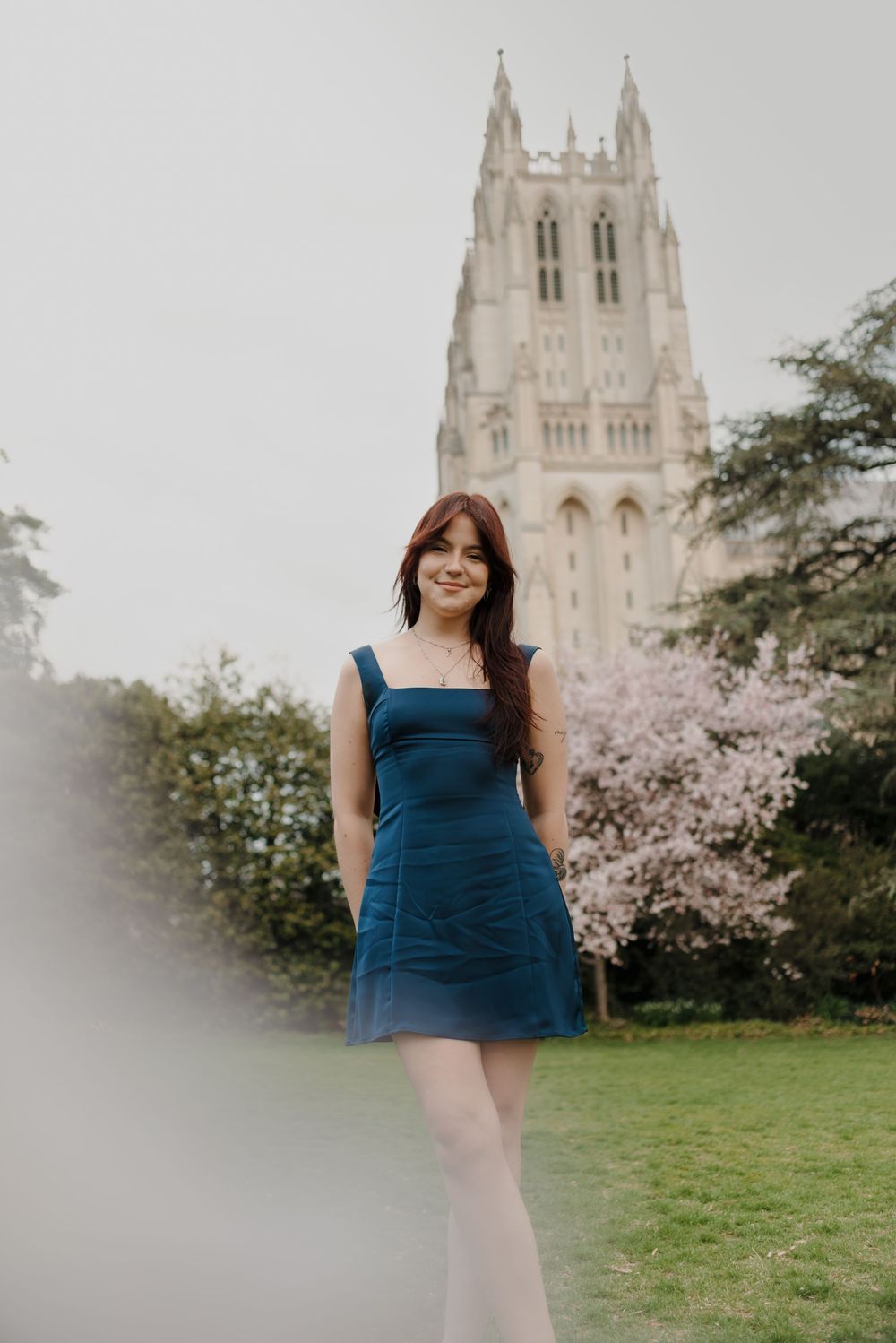 A graduation portrait with a majestic Gothic cathedral and cherry blossoms in the background.