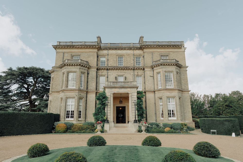 Exterior view of a grand stone mansion with classical architecture and manicured grounds.