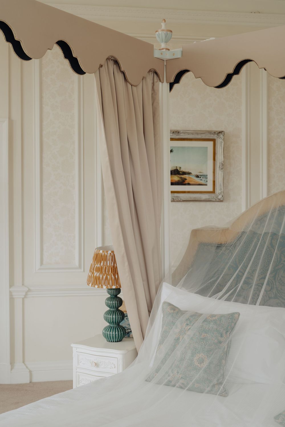 Serene bedroom interior with soft curtains and decorative mosquito net over white bed.