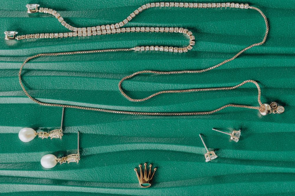 Collection of delicate silver jewelry pieces displayed on a bright turquoise green background.