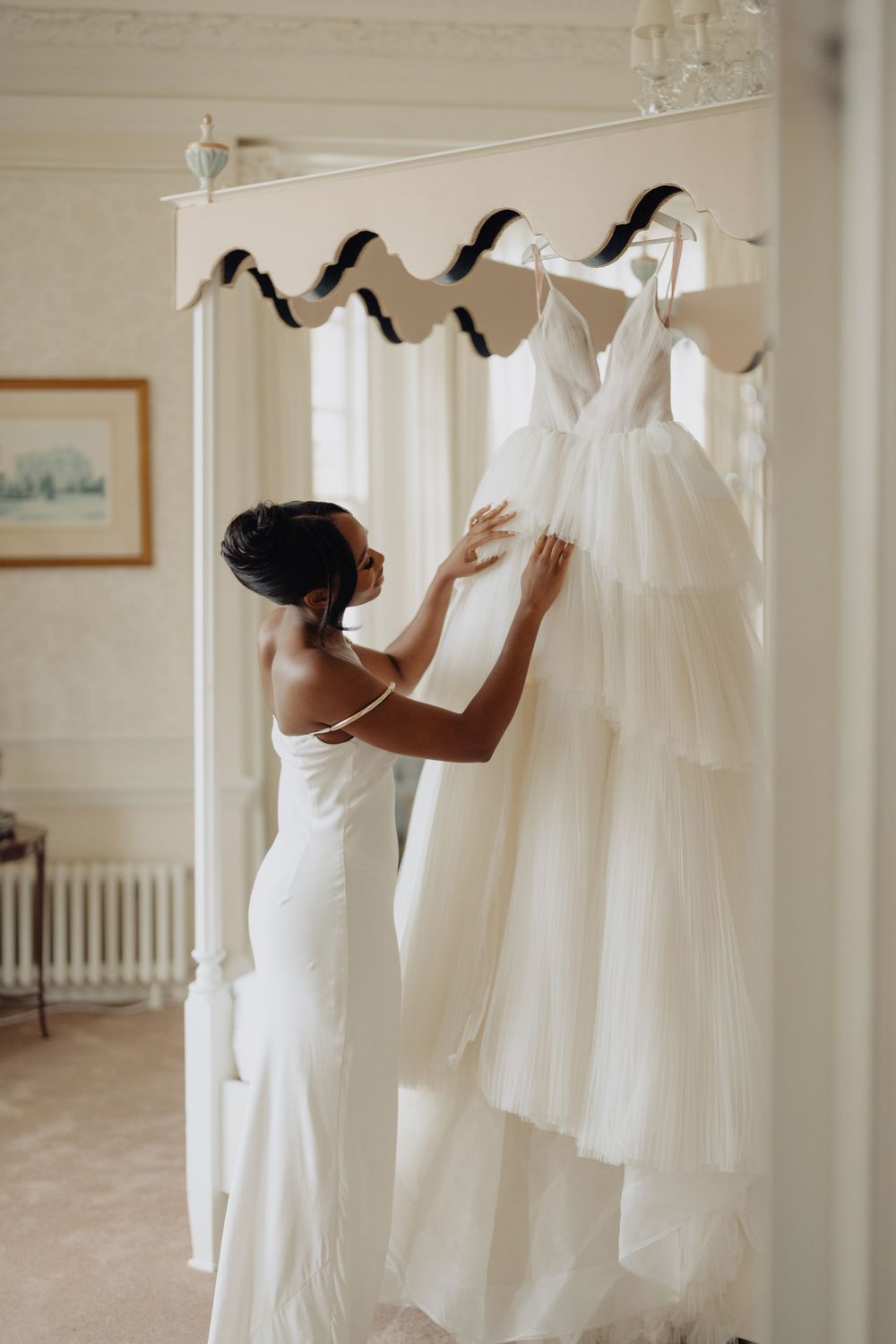 Wedding dresses hanging on display in elegant white bridal preparation room.