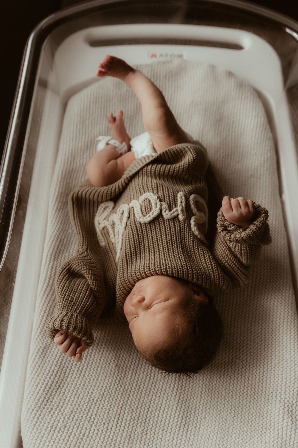 A baby wearing a cozy brown knit sweater lies on a white textured surface in a series of lifestyle photos.
