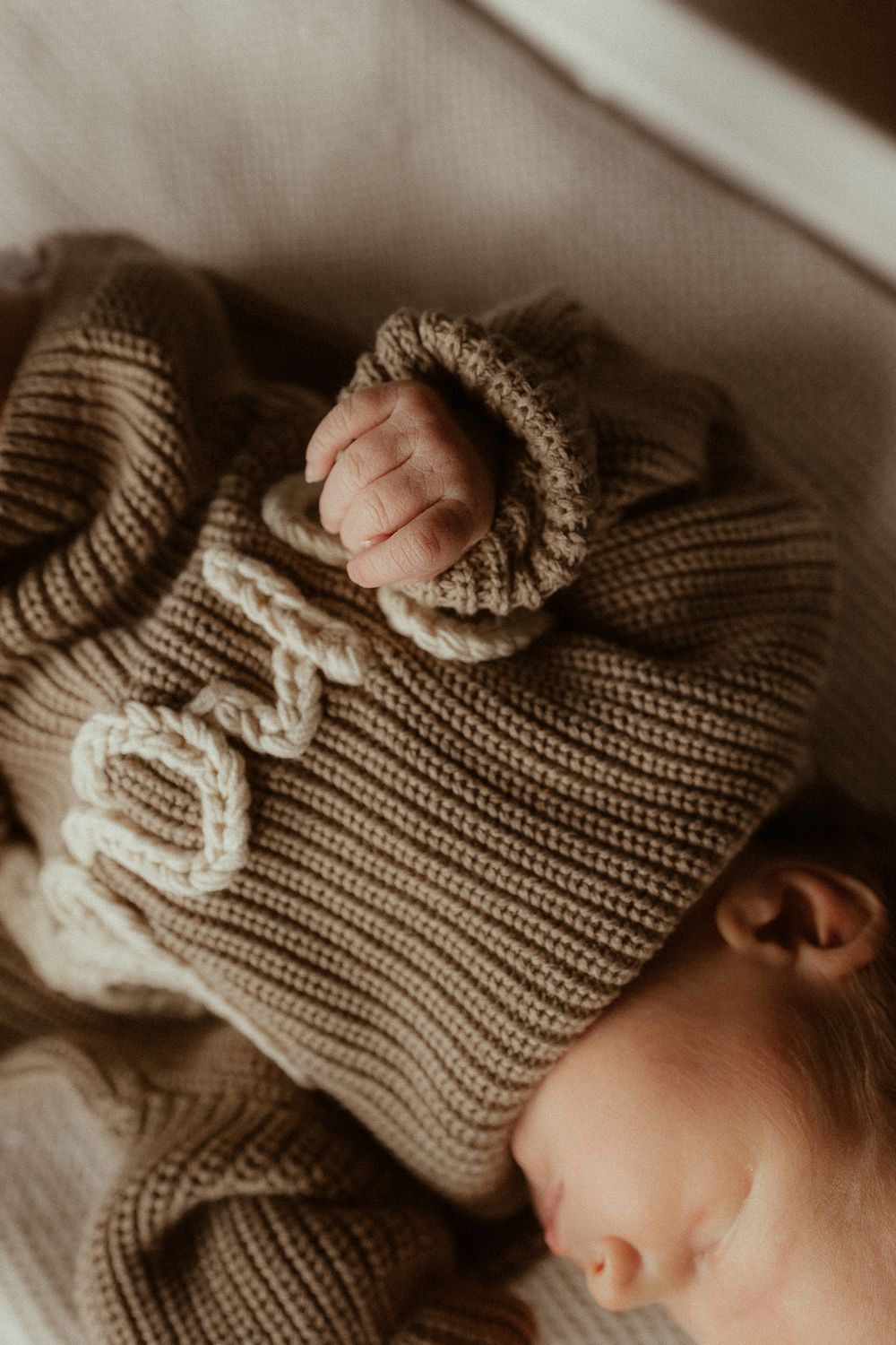 Close-up view of a knitted beige hat with delicate details in warm, moody lighting.