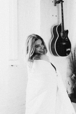 High-key portrait in white room with guitar hanging on wall.