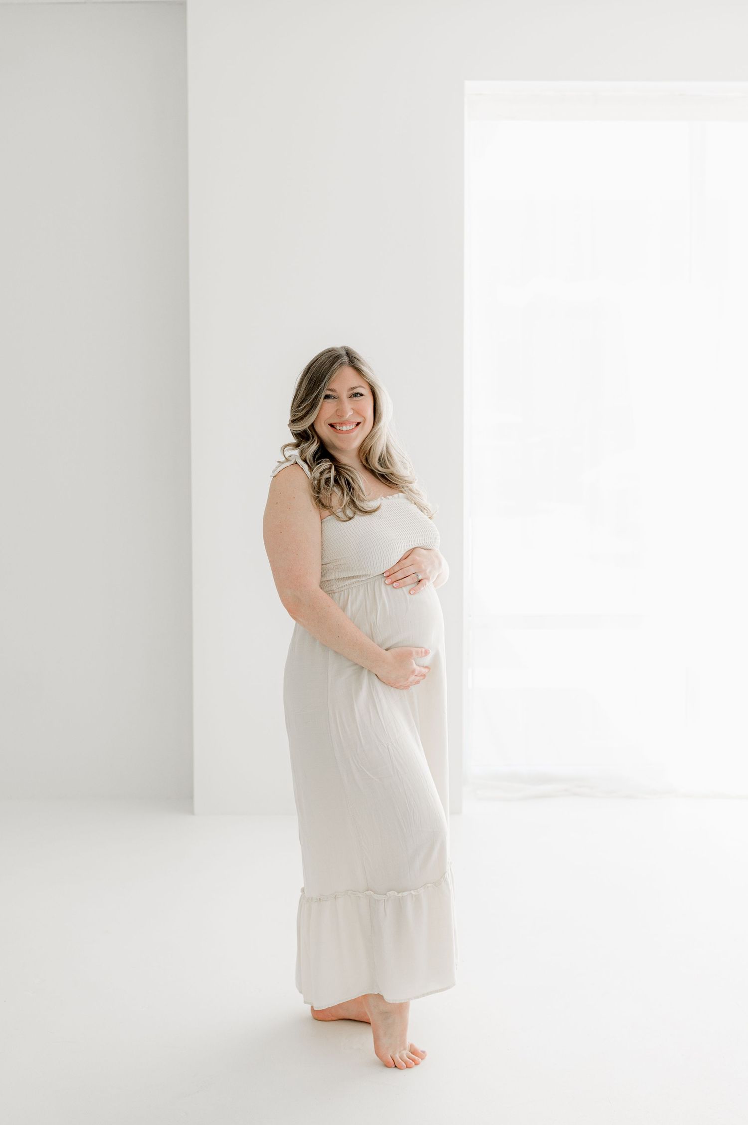 Expectant mother in flowing dress against bright background for maternity Jacksonville, FL maternity session.