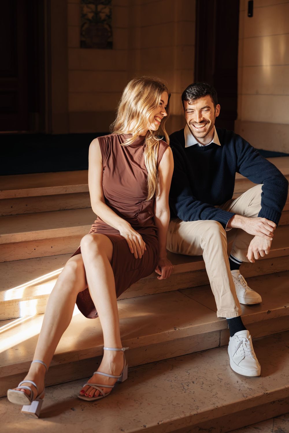 Two people sitting on concrete steps in dramatic natural lighting.