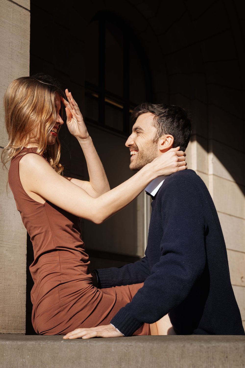 Two people share a playful dance moment in dramatic sunlight and shadows.