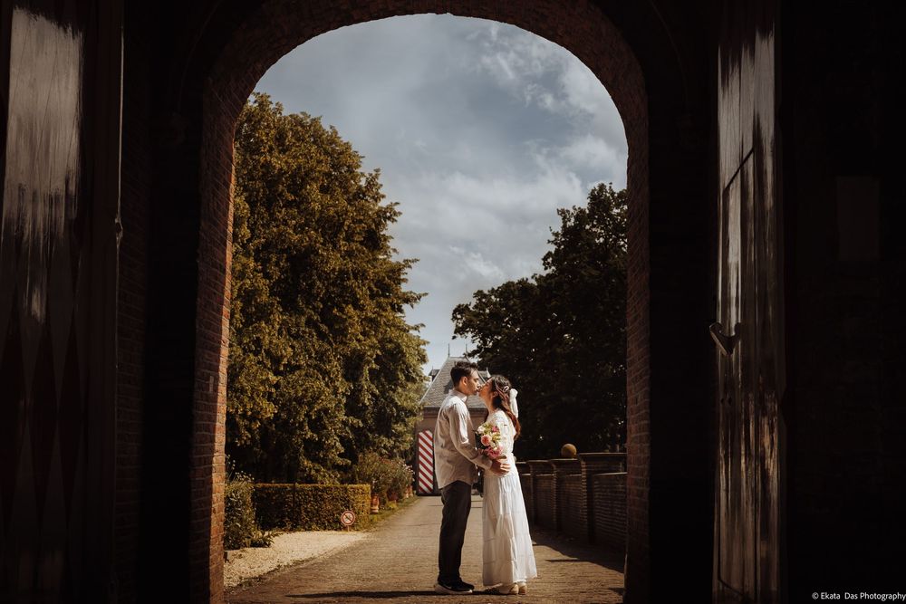 Couple sharing a romantic kiss framed by a rustic stone archway at a countryside wedding venue.