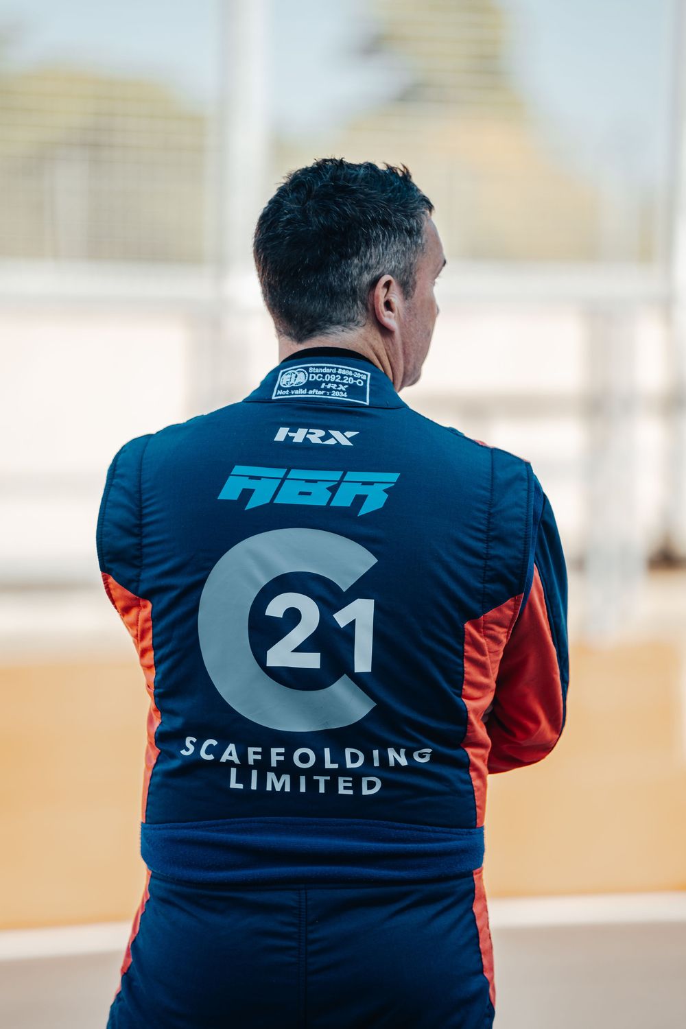 Back view of racing team members wearing navy blue uniforms with number 21 and ASR Scaffolding branding.
