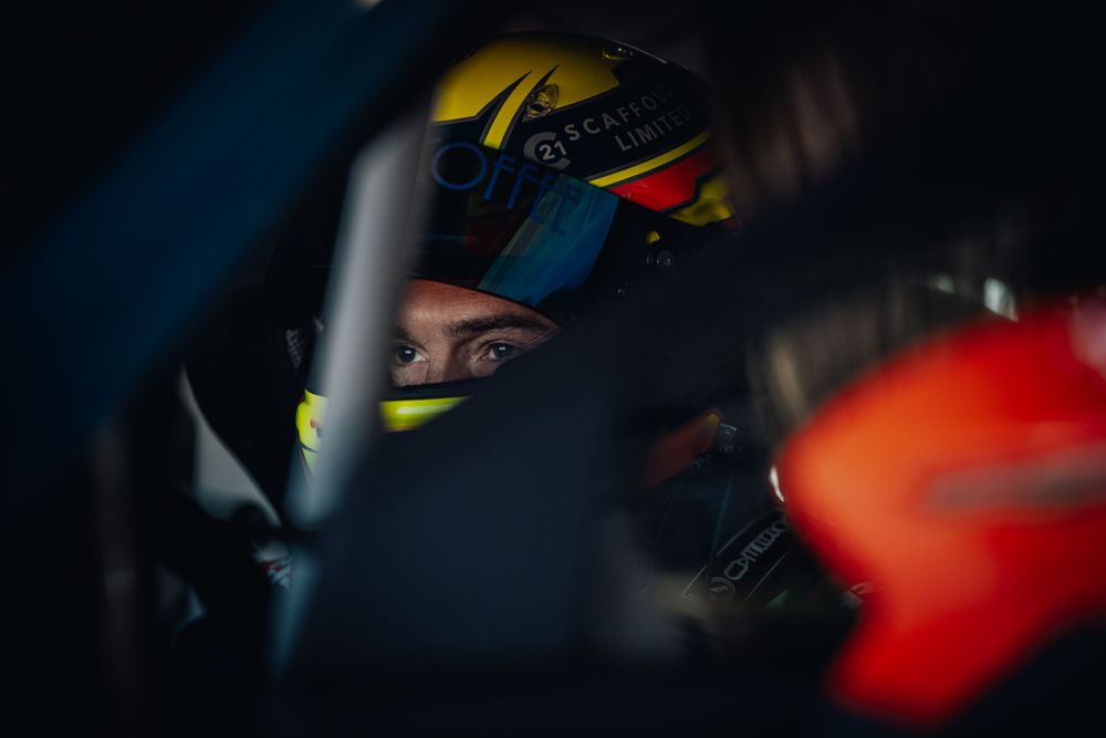 Racing driver in a helmet focuses intently during a motorsport competition.
