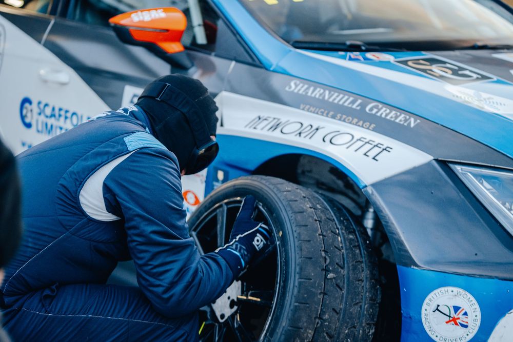 Close-up of mechanics working on Formula 1 race cars in pit lane during a motorsport event.