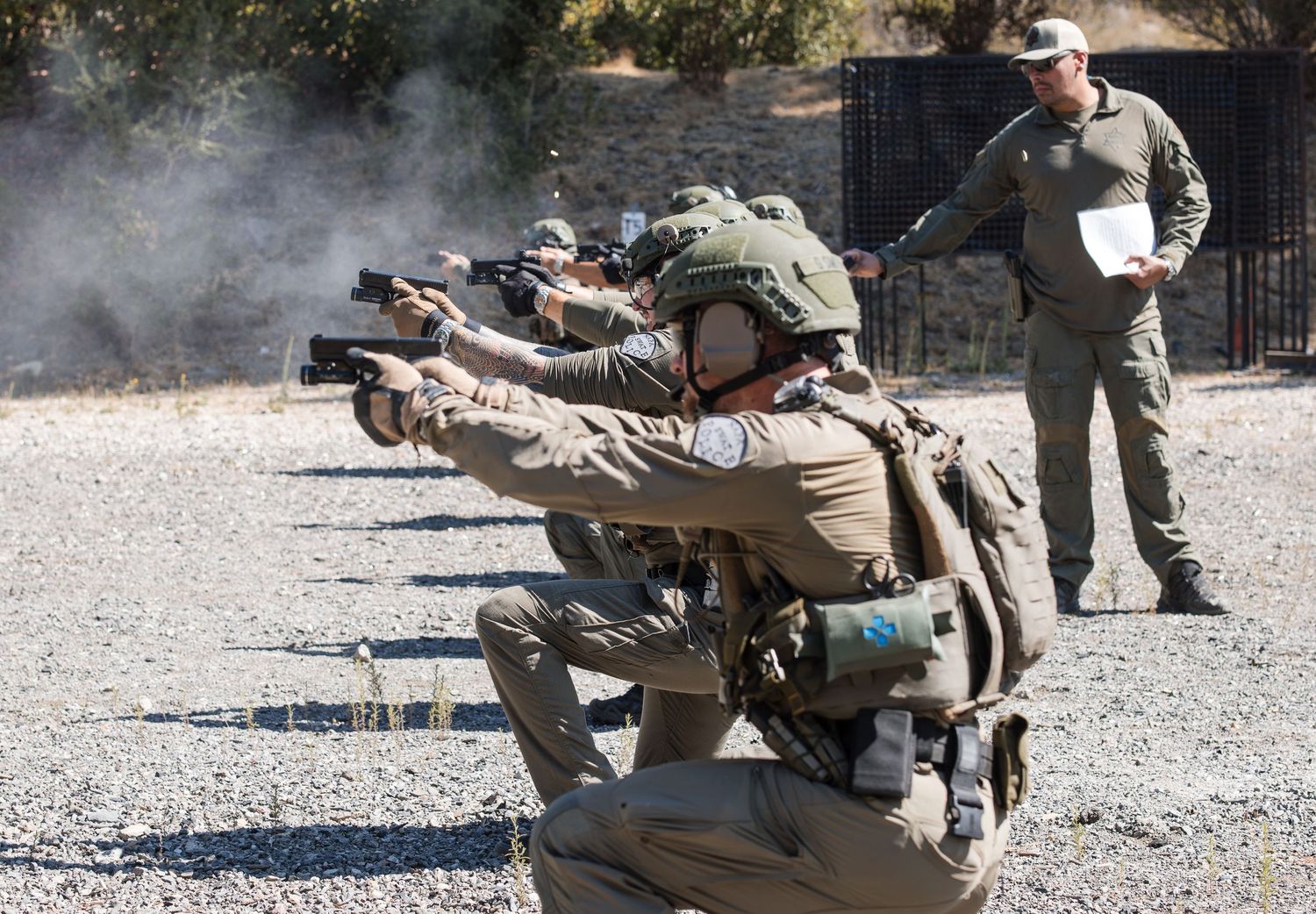 Military or tactical training exercise with personnel in prone shooting positions.
