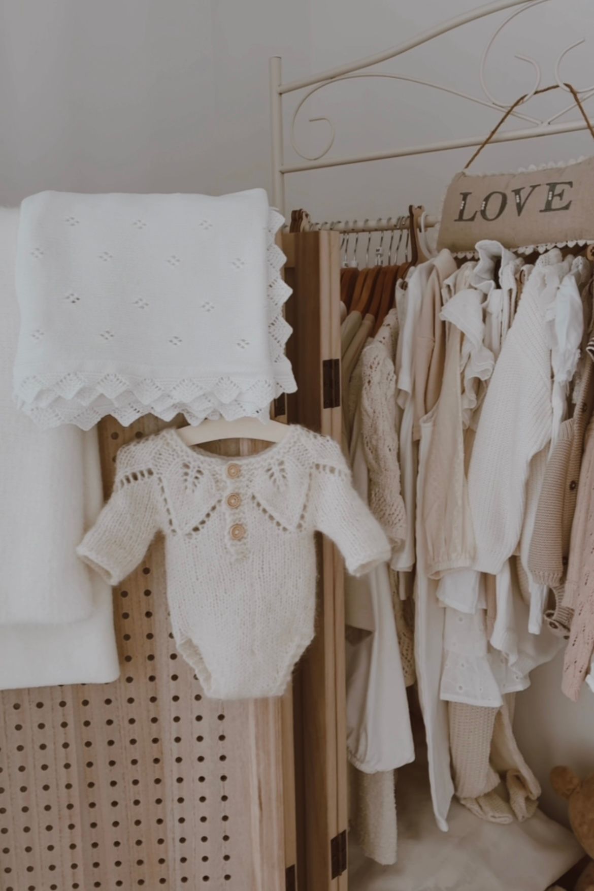 White baby romper with delicate pink embroidered floral design and ruffle details on straps.