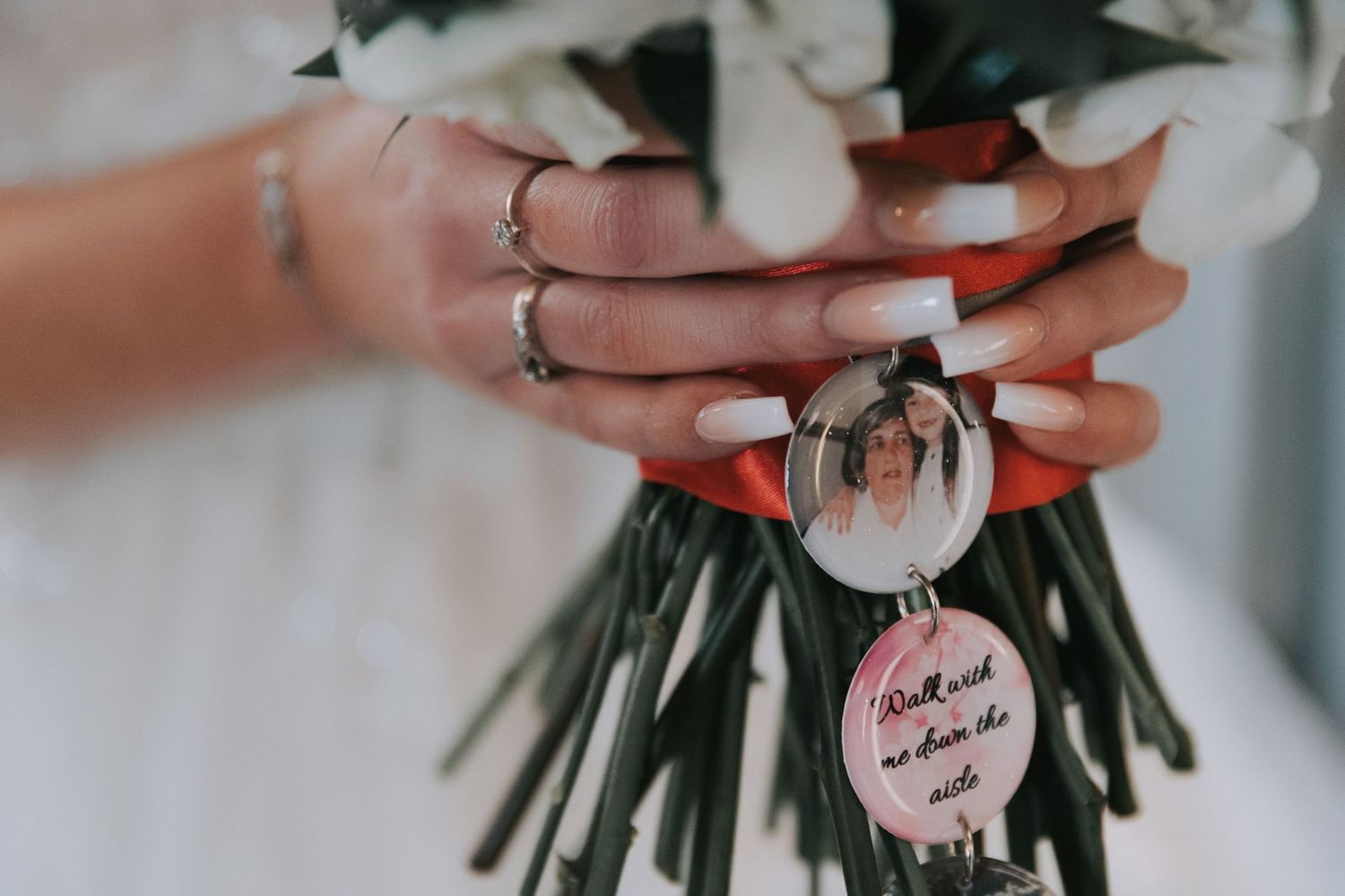 Elegant white floral bouquet with greenery held against a light background with a blurred circular tag.