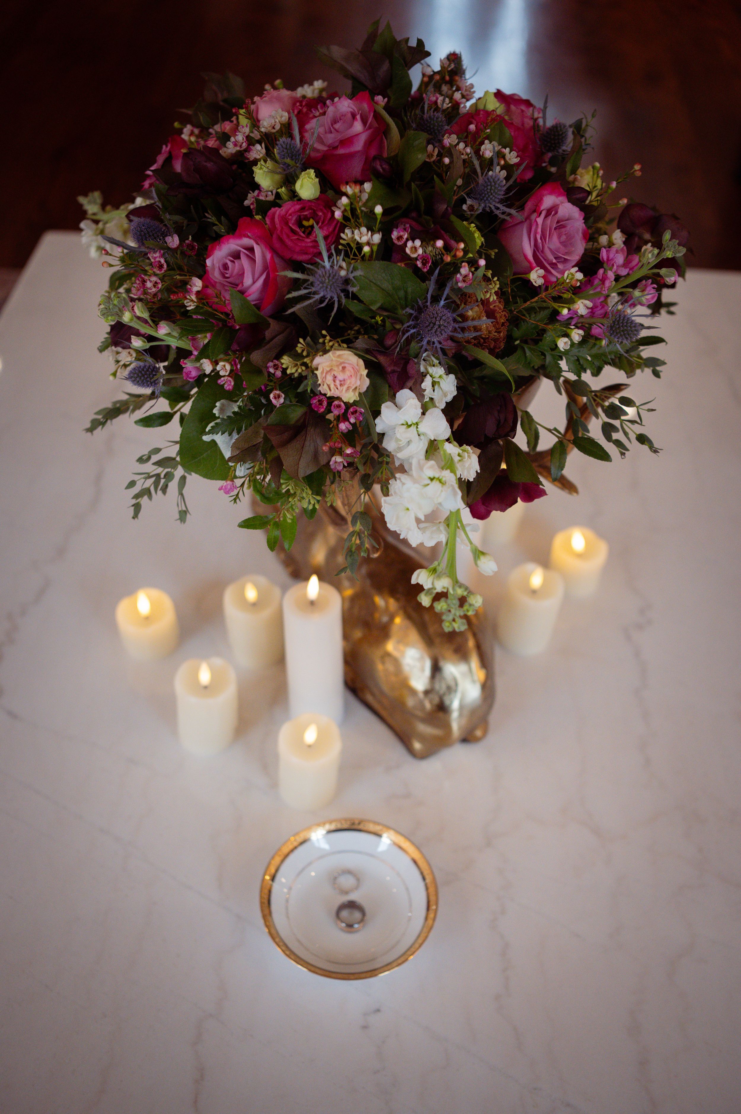 A romantic table setting with glowing candles and a lush floral centerpiece featuring pink roses and mixed blooms.