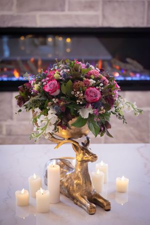 A romantic table setting with golden deer figurines holding pink and white floral arrangements surrounded by glowing candles.