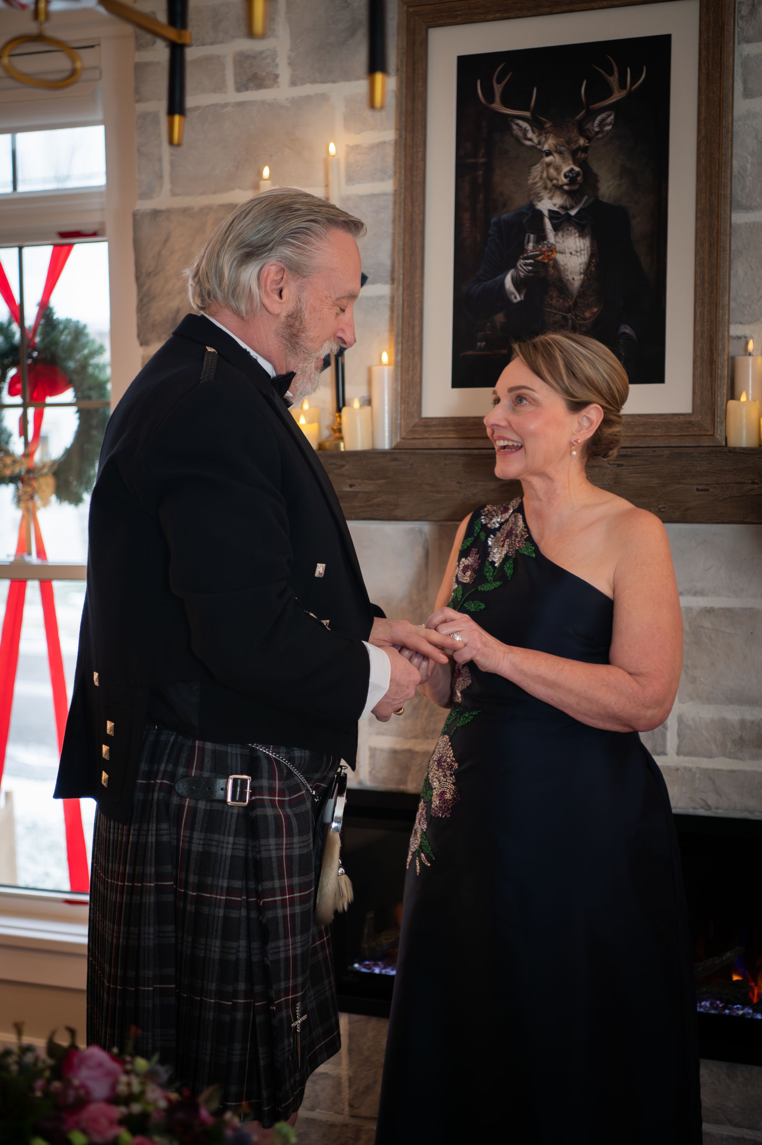 A couple in formal attire dance together at an elegant venue decorated for the holidays.
