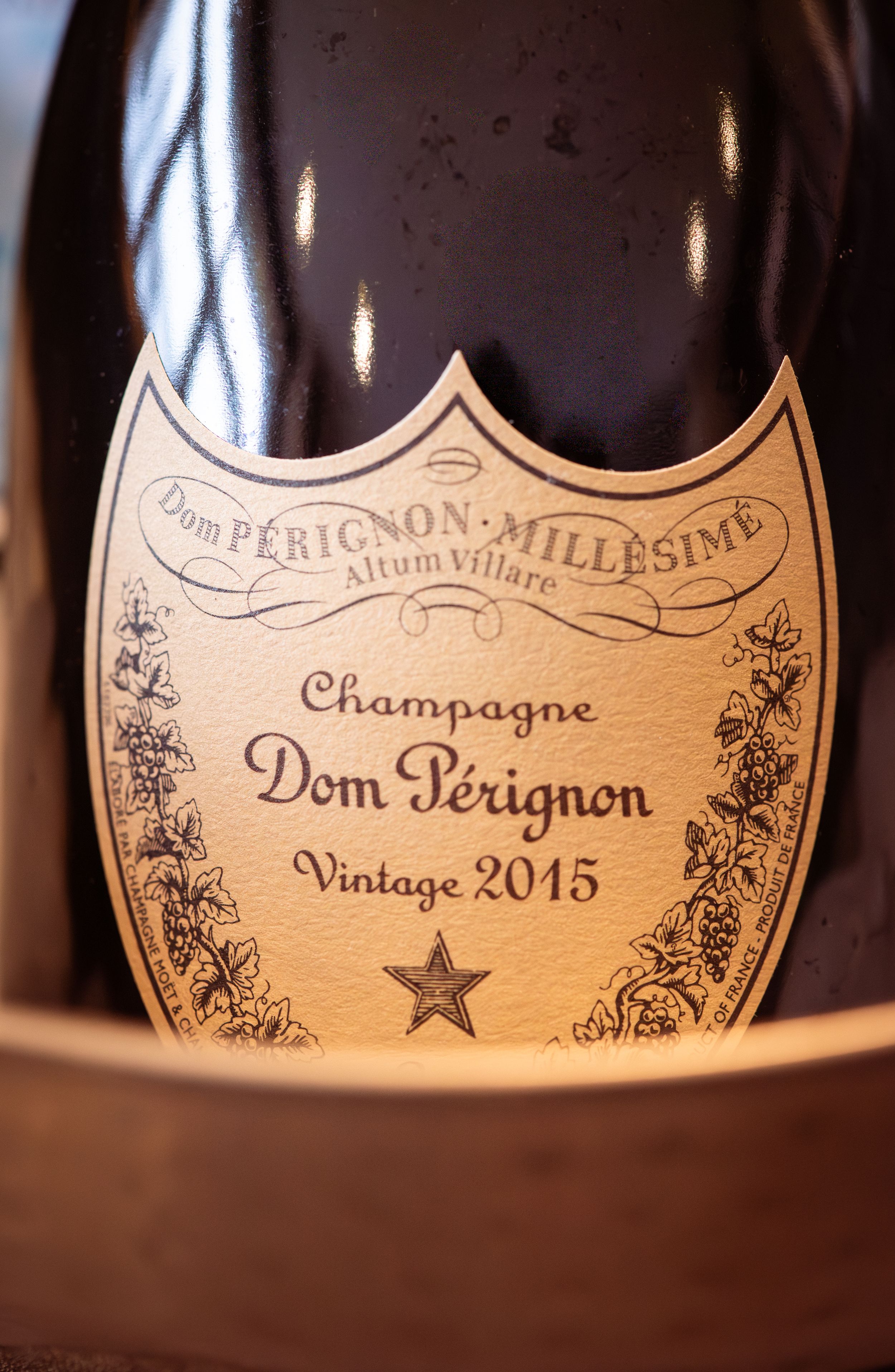 Close-up details of Dom Perignon champagne bottle labels showing vintage 2015 text and ornate designs.