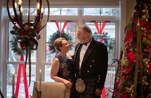 Elegantly dressed guests mingle and socialize at a formal holiday party with festive Christmas decorations.
