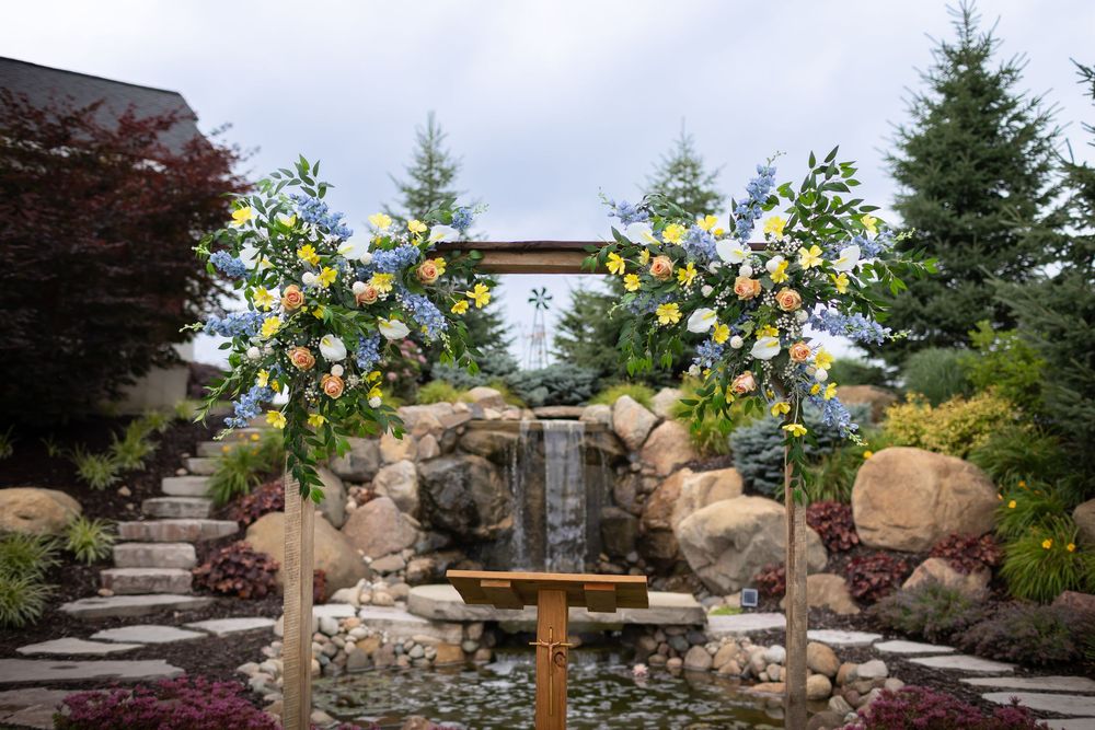 Outdoor wedding ceremony setup with floral arrangements and natural stone landscaping in a garden setting.