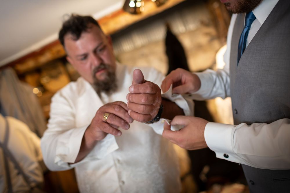 Close-up shot of hands adjusting formal attire in warm indoor lighting.